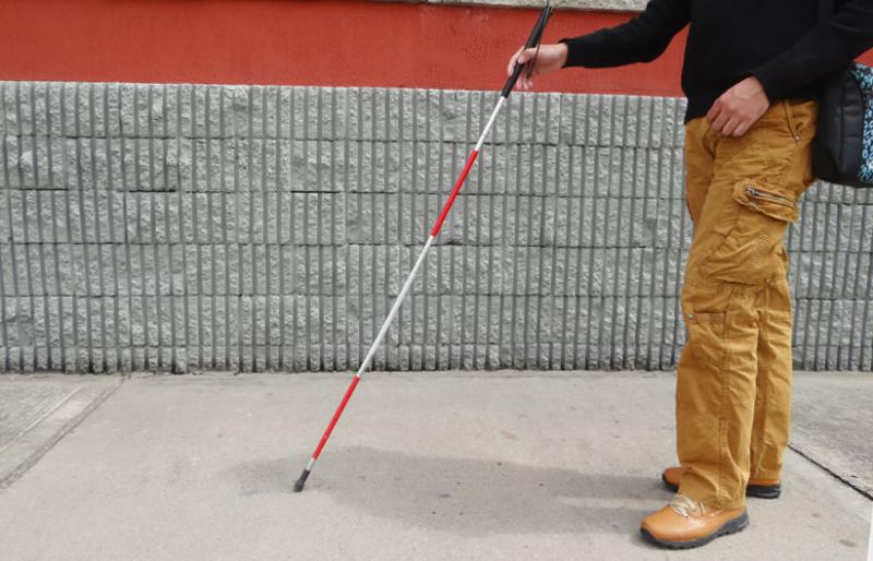 Persona con discapacidad visual caminando con su bastón