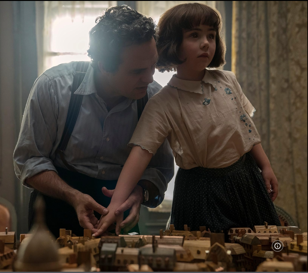 Mark Rufallo en su papel sostiene la mano de Sutton guiando sus dedos por una maqueta gigante de casas de madera