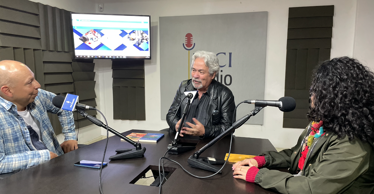 cabina, a la izquierda está jota mirando fijamente al invitado Manuel, quien está en el centro, a la derecha está claudia quien también lo mira fijamente