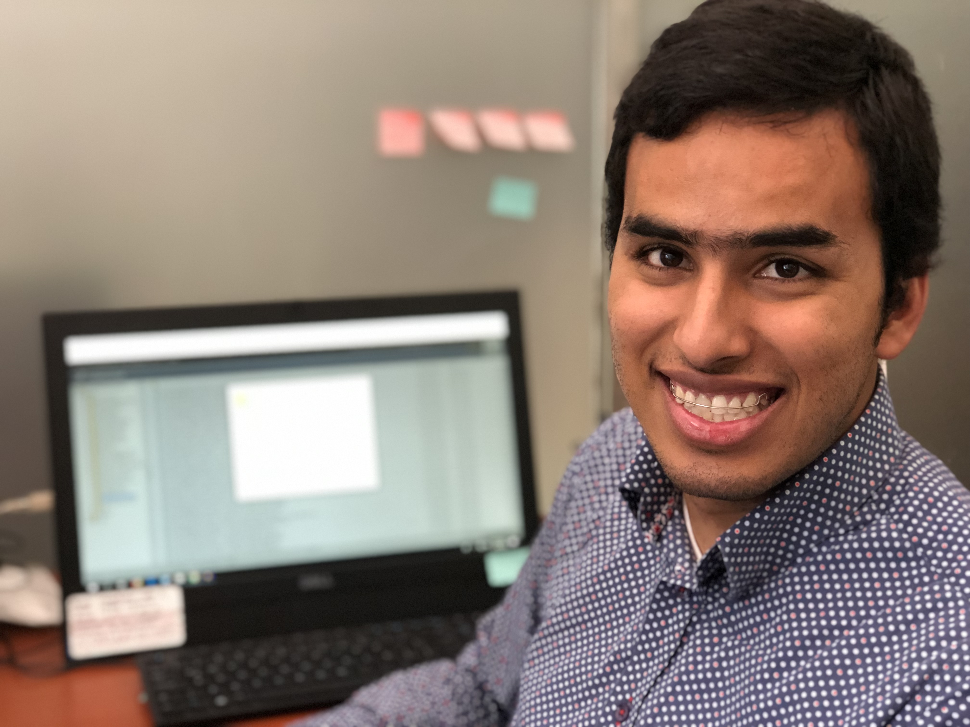 Imagen de Manuel Sanchez en una oficina,  frente al computador, él sonríe 