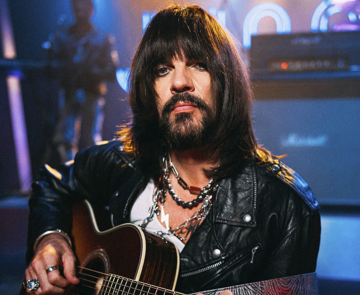 Juanes maquillado nos recuerda la época del rock glam, en sus manos sostiene una guitarra acústica