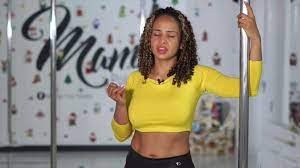 andrea en primer plano  tiene sus ojos cerrados, su mano izquierda reposa en el pole 