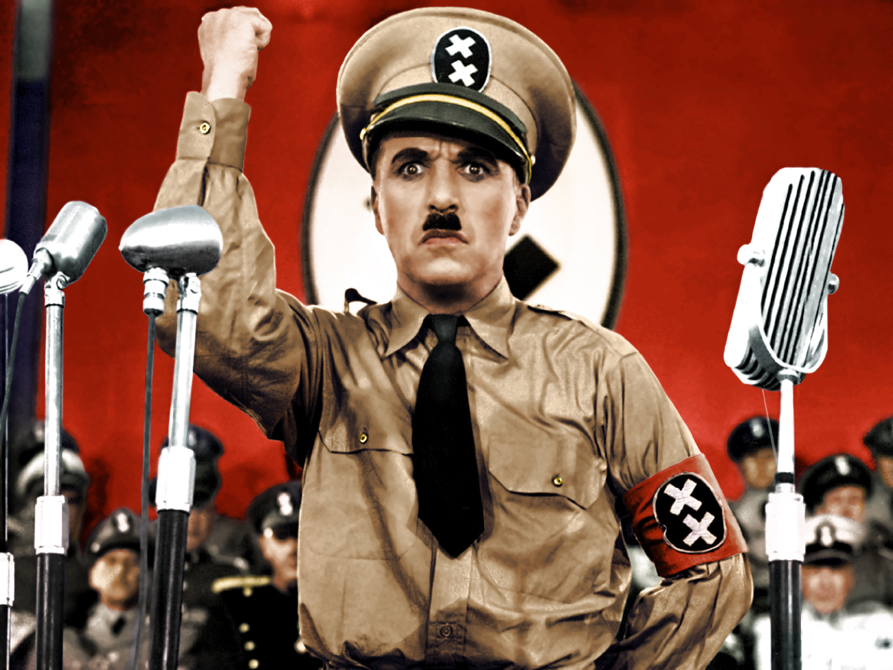 fotografía a color de Charles Chaplin en su interpretación del dictador viste su uniforme su mano derecha está elevada simulando dando un discurso 