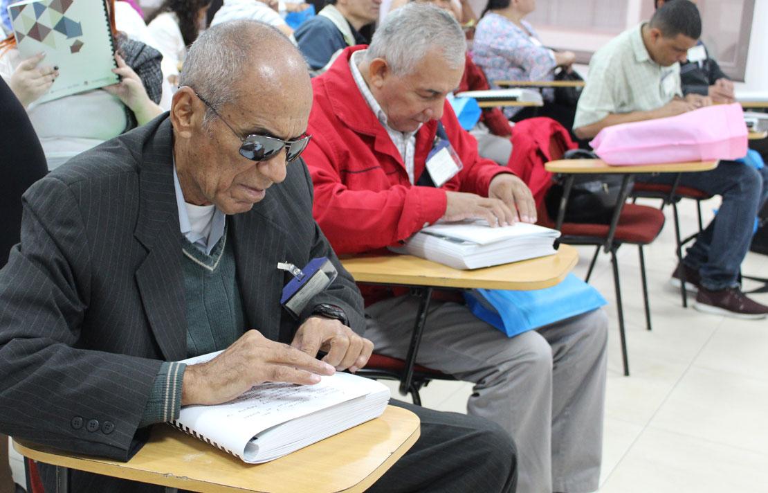 Imagen evento centro cultural, varias personas con discapacidad visual pasan sus manos sobre escritos en braille