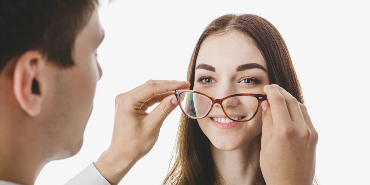 una mujer sonríe mientras el optómetra le realiza un examen visual 