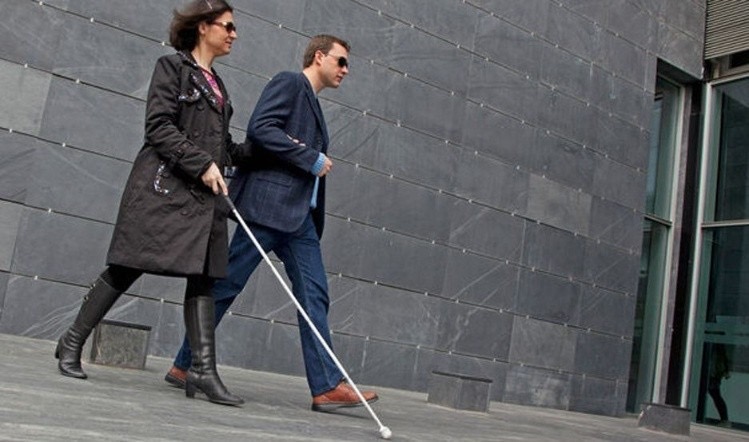 una mujer ciega es guiada por un ciudadano