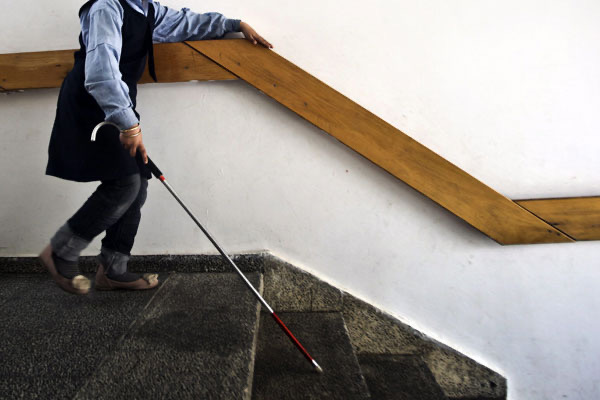 una niña ciega se guía por un barandal 