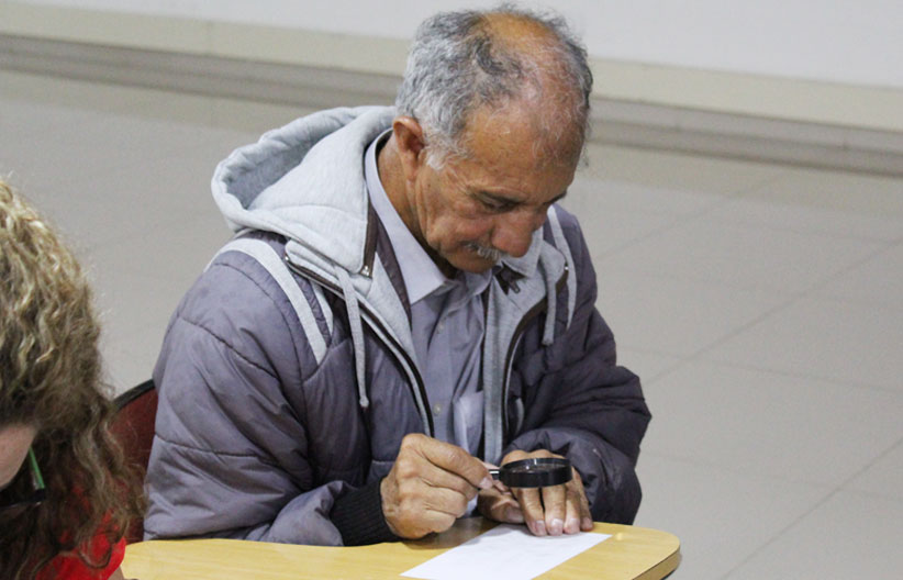 Asistente al taller de braille con una lupa en la mano