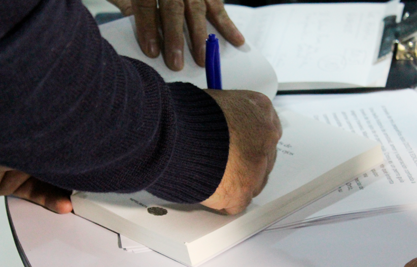 Fotografía, Emilio Ortiz firmando libros de los asistentes al conversatorio