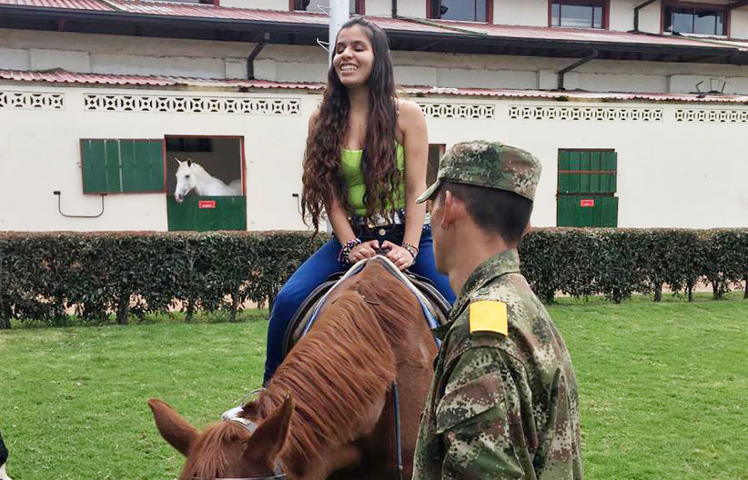 Persona con discapacidad visual sobre un caballo en la Escuela de Equitación del Ejército