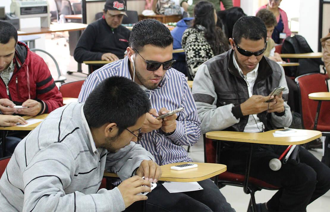 Fotografía personas con discapacidad visual interactuando con celulares