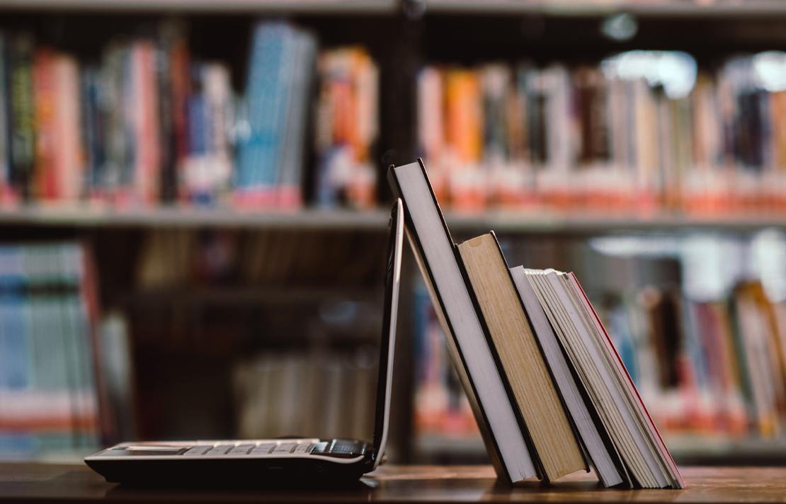 Fotografía - Libros recostados contra la pantalla de un computador portatil