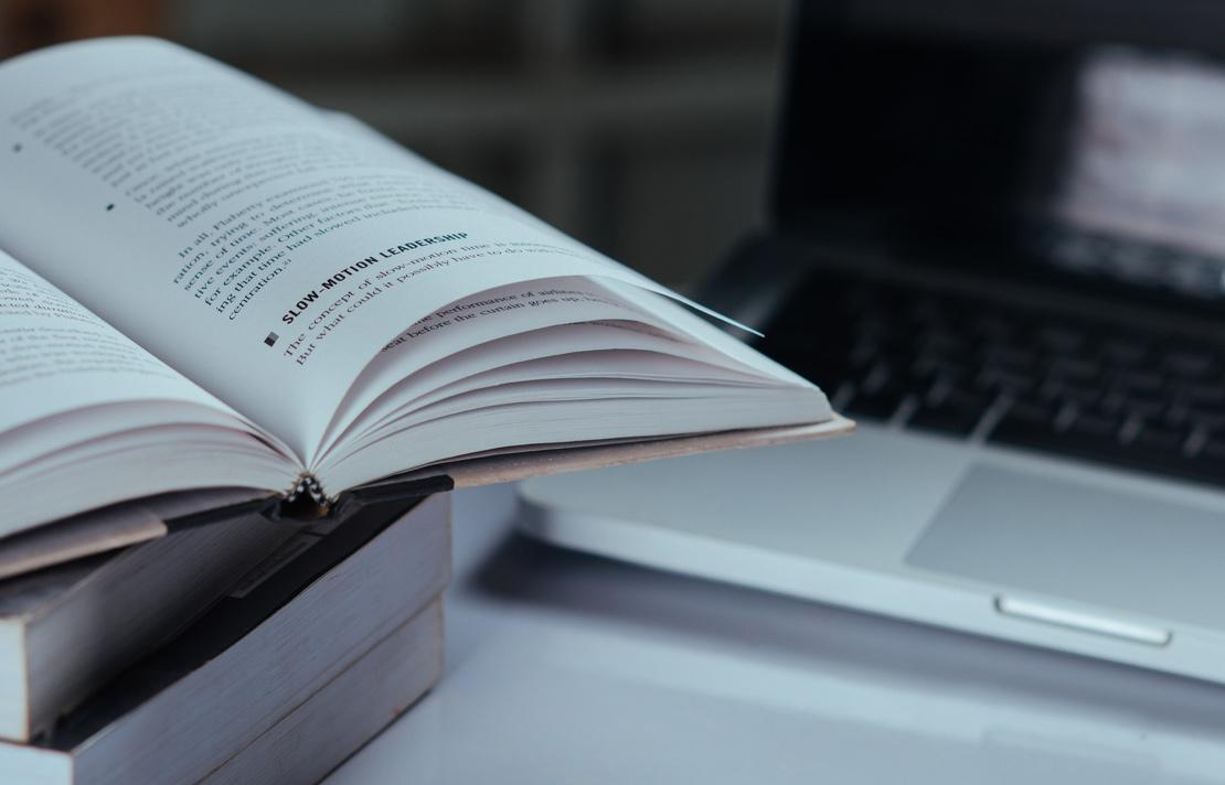 Fotografía - Libros sobre escritorio y un computador de fondo