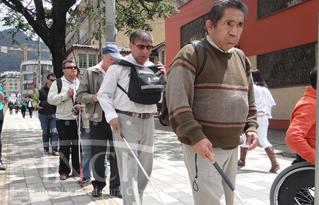 personas con discapacidad visual  cruzando una calle concurrida