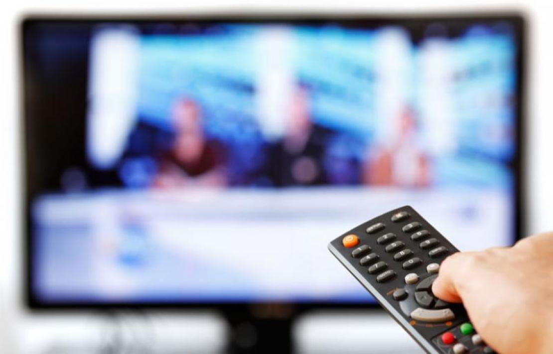 Persona frente a un televisor con un control remoto