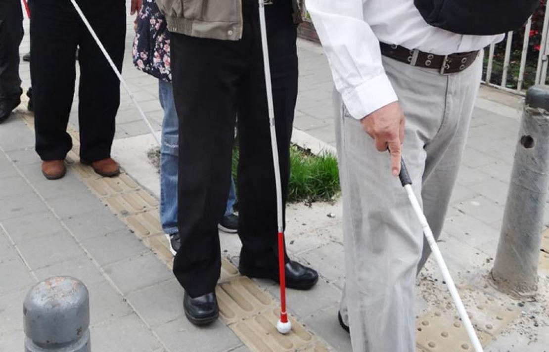 Personas con discapacidad visual caminando por una linea de tabletas podotáctiles