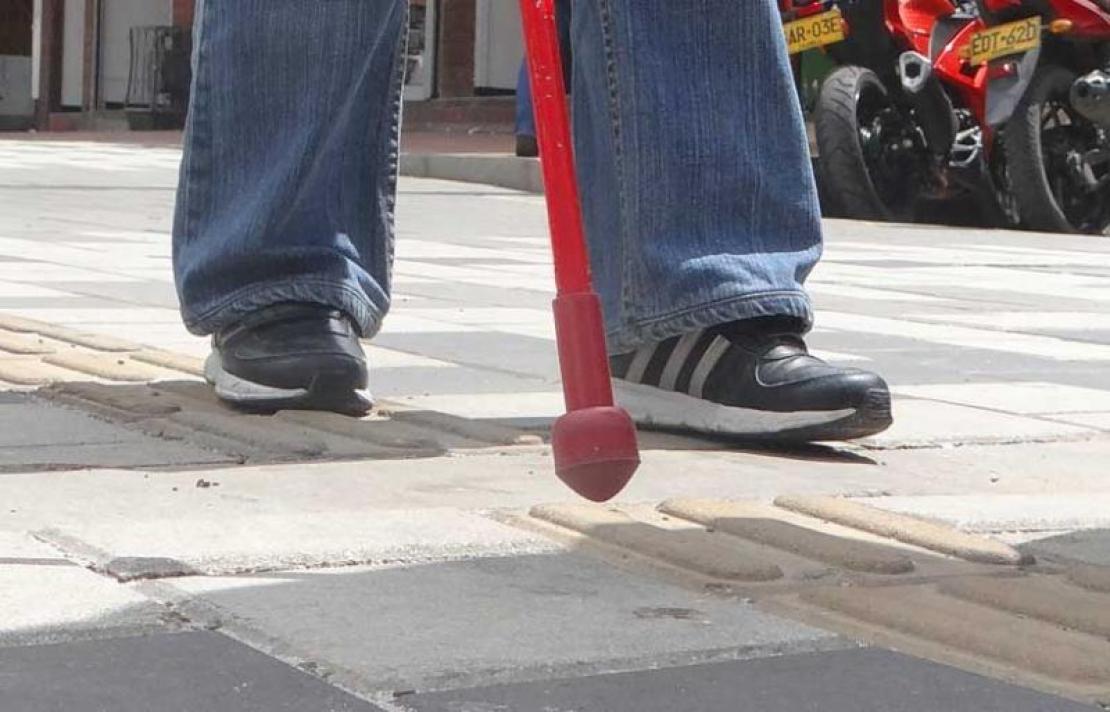 Persona con discapacidad visual caminando con su bastón