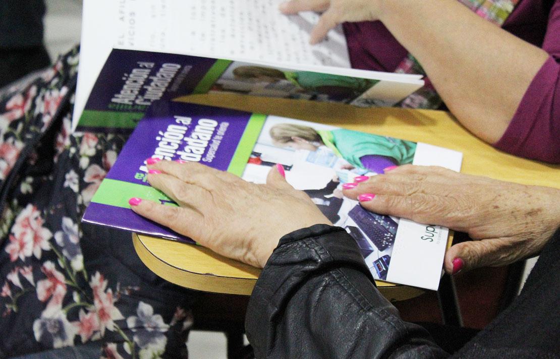 Fotografía, persona con discapacidad visual leyendo cartilla de atención al ciudadano