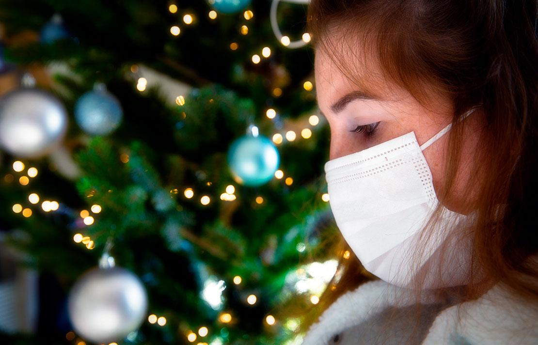 Fotografía, persona junto al árbol de navidad con tapabocas