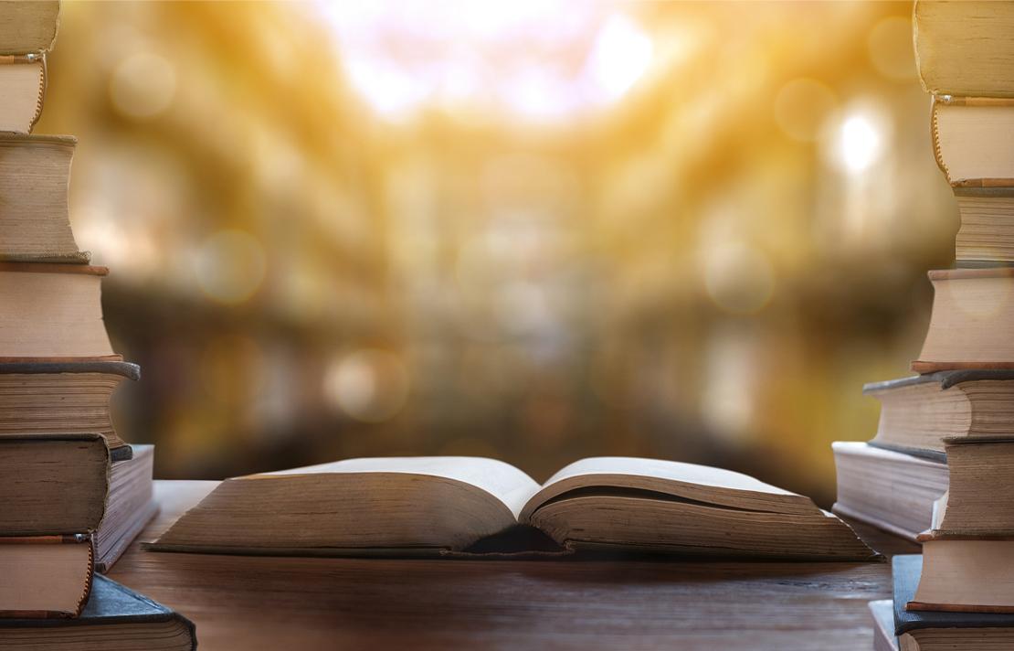 Fotografía - Libro abierto con varios libros apilados al lado