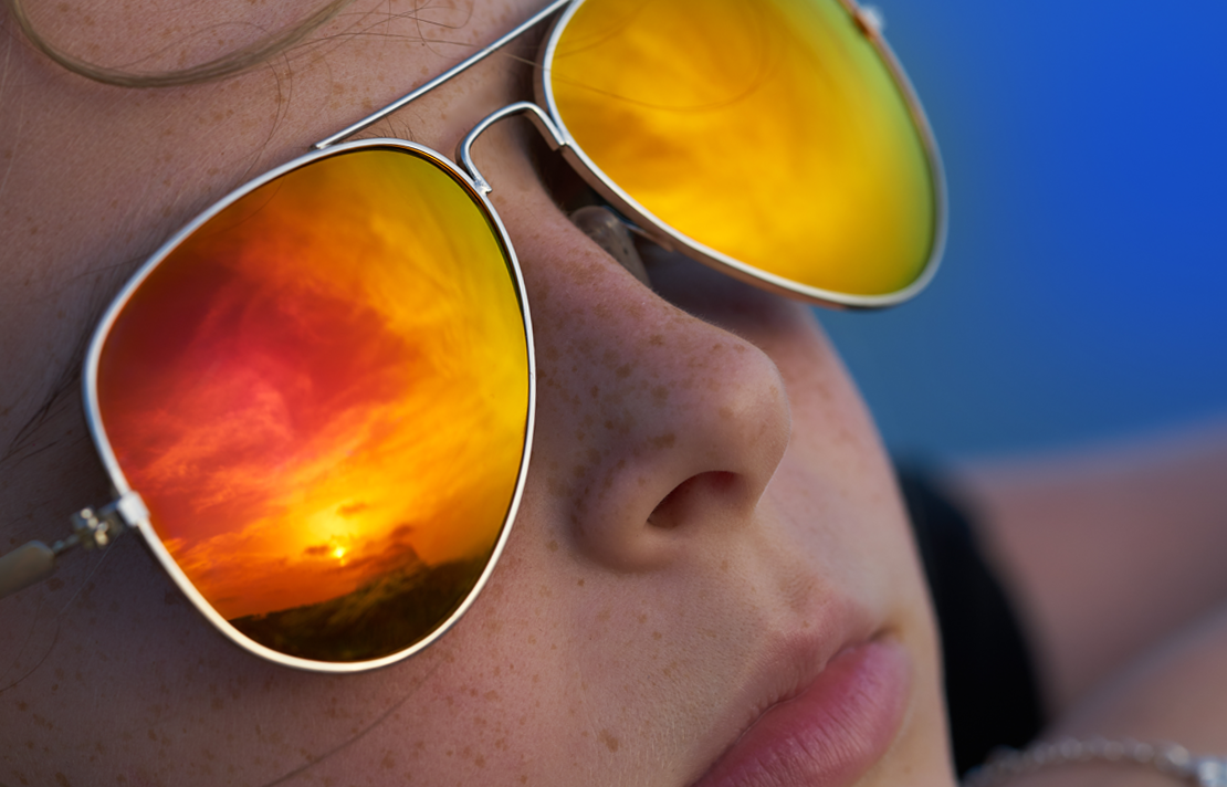 Mujer con lentes oscuros mirando una puesta de sol