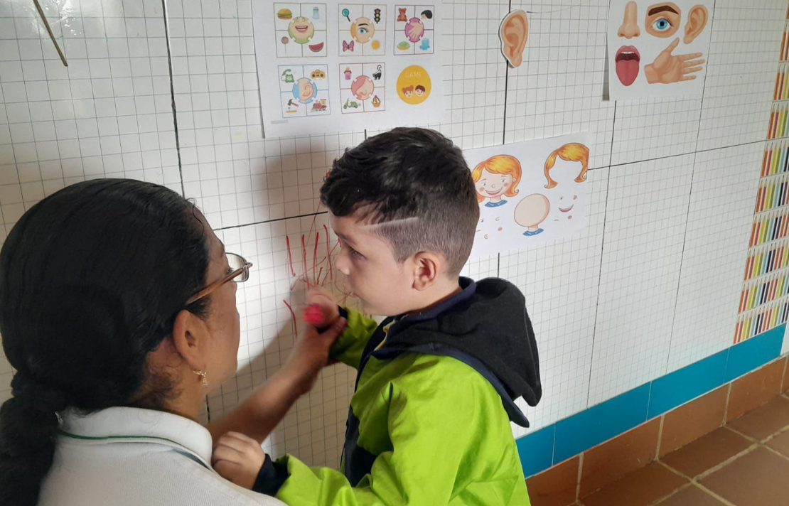 Niño con discapacidad visual acompañado por una docente en un aula de clases