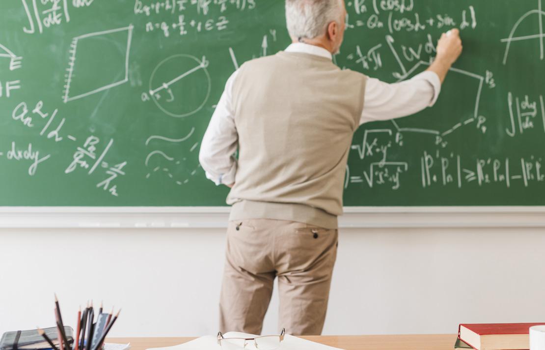 Profesor de matemáticas explicando ejercicios en un tablero
