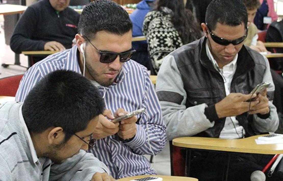 Personas con discapacidad visual manipulando teléfonos inteligentes para acceder a información