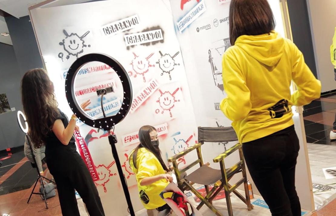 3 mujeres en medio de un set de grabación utilizando un teléfono inteligente