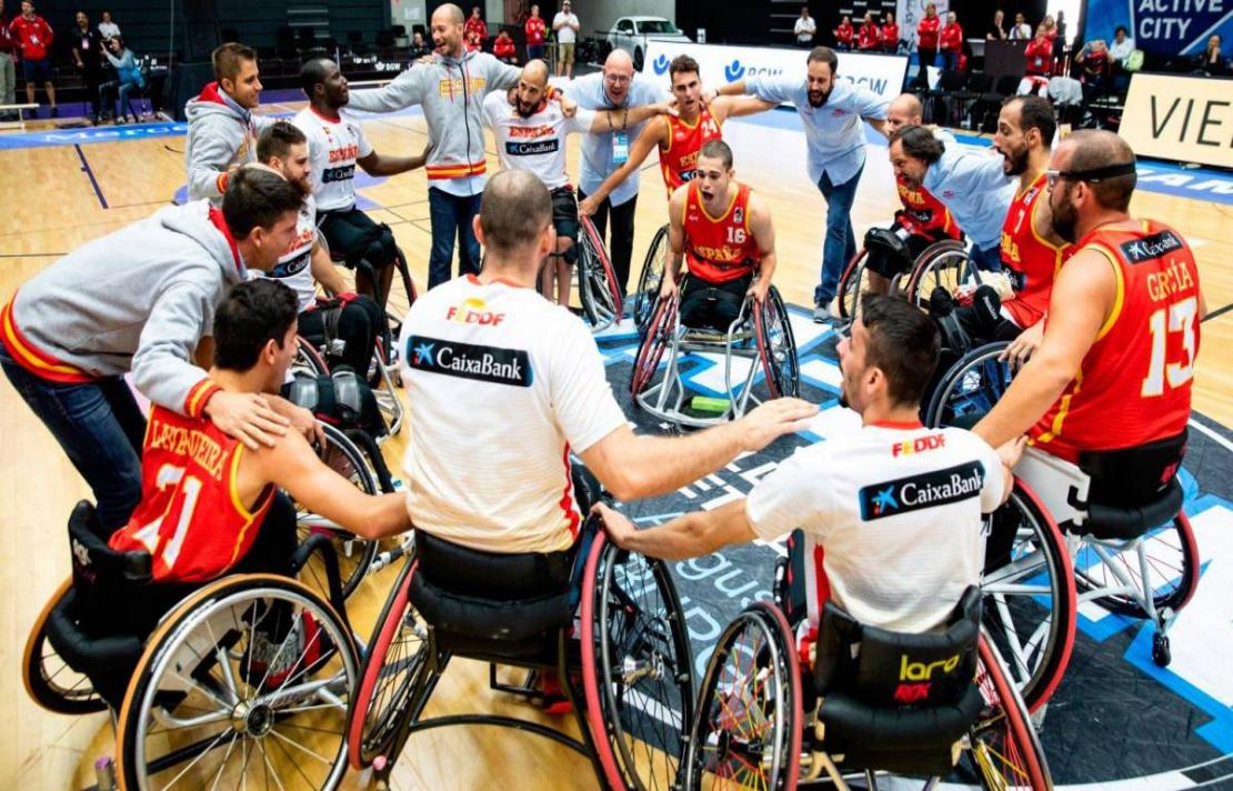 imagen, un equipo de baloncesto en silla de ruedas hace un círculo en la cancha, se ven alegres y emocionados