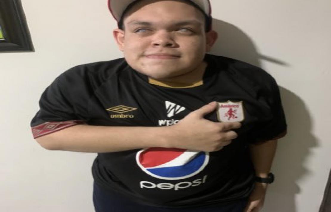 imagen de Jhonathan Daza el sonríe, viste una camisa del América de Cali, su mano está en su pecho sobre el escudo del América,