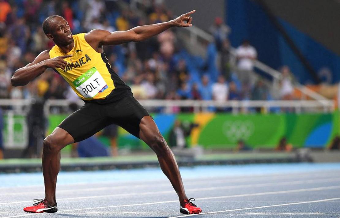 Imagen Usain Bolt, el viste el uniforme amarillo y negro de Jamaica, con sus brazos apunta al cielo
