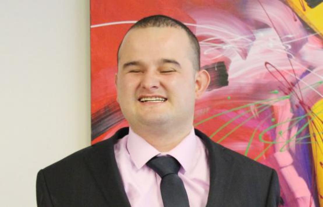 Imagen Sergio Gonzalez, él viste un traje oscuro camisa rosada y corbata negra, sonríe