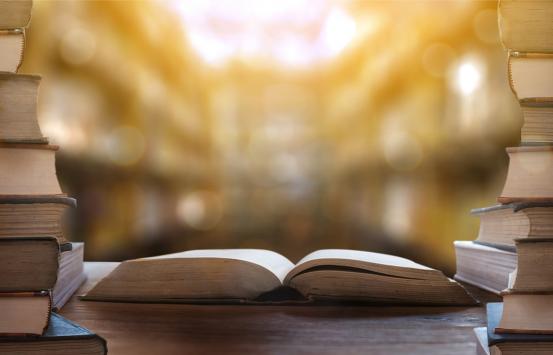 Fotografía - Libro abierto con varios libros apilados al lado