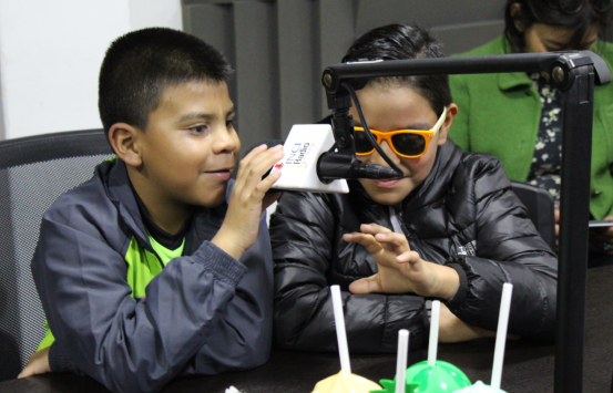 niños con discapacidad visual en la cabina de inciradio uno de ellos sostiene con su mano un micrófono