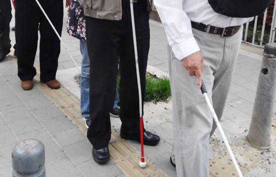 Personas con discapacidad visual caminando por una linea de tabletas podotáctiles